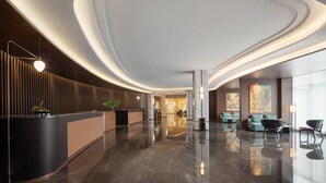 Un lobby moderno con un mostrador de recepción curvo, zona de estar y amplias ventanas.