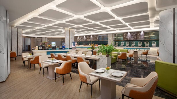 Un restaurante moderno con un diseño de techo original, suelo de mármol y diversas opciones de asientos, incluidas mesas y sillas.