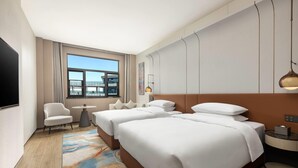 Una habitación de hotel con dos camas, televisor, una mesita y una silla.