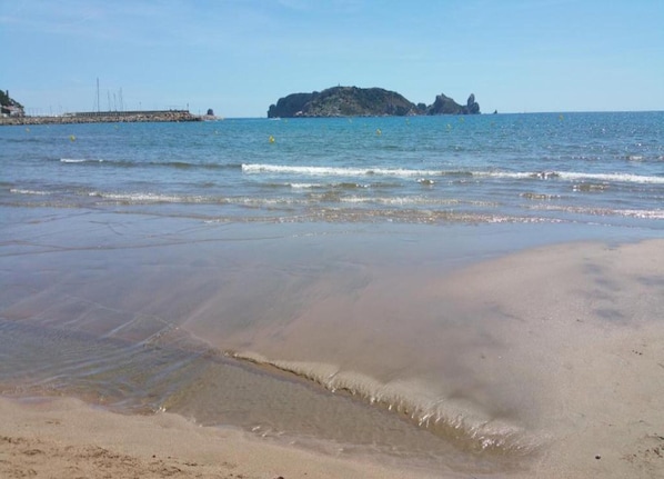 A beach with clear water, a sandy shore, and a distant rocky island. - Apartment in Estartit Near sea Beach (Torroella de Montgrí)