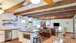 A spacious kitchen with wooden beams, a central island, and a dining area with a television.