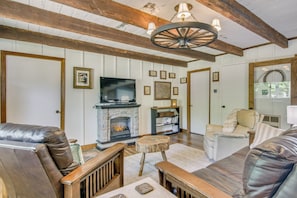 Una sala de estar con chimenea, sofás de cuero, muebles de madera y un televisor.