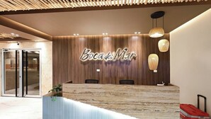 En receptionsdisk med en bakgrund av träpaneler och en skylt med texten ”Boca de Mar”.