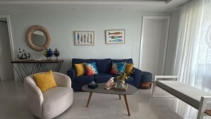 A modern living room with a sofa, armchair, coffee table, and artwork on the wall. - beach paradise ground floor Cabarete (Cabarete)