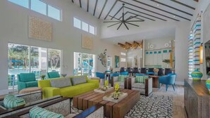 A spacious living area with a bright green sofa, multiple seating options, a wooden coffee table, and a view of an outdoor swimming pool.