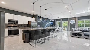 A modern kitchen with a central island, bar stools, and a dining area with a sofa and chairs.