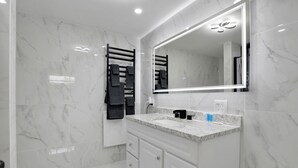 A modern bathroom with a marble floor, a large mirror, and a towel rack. - Overlook Hotel (Saugerties)