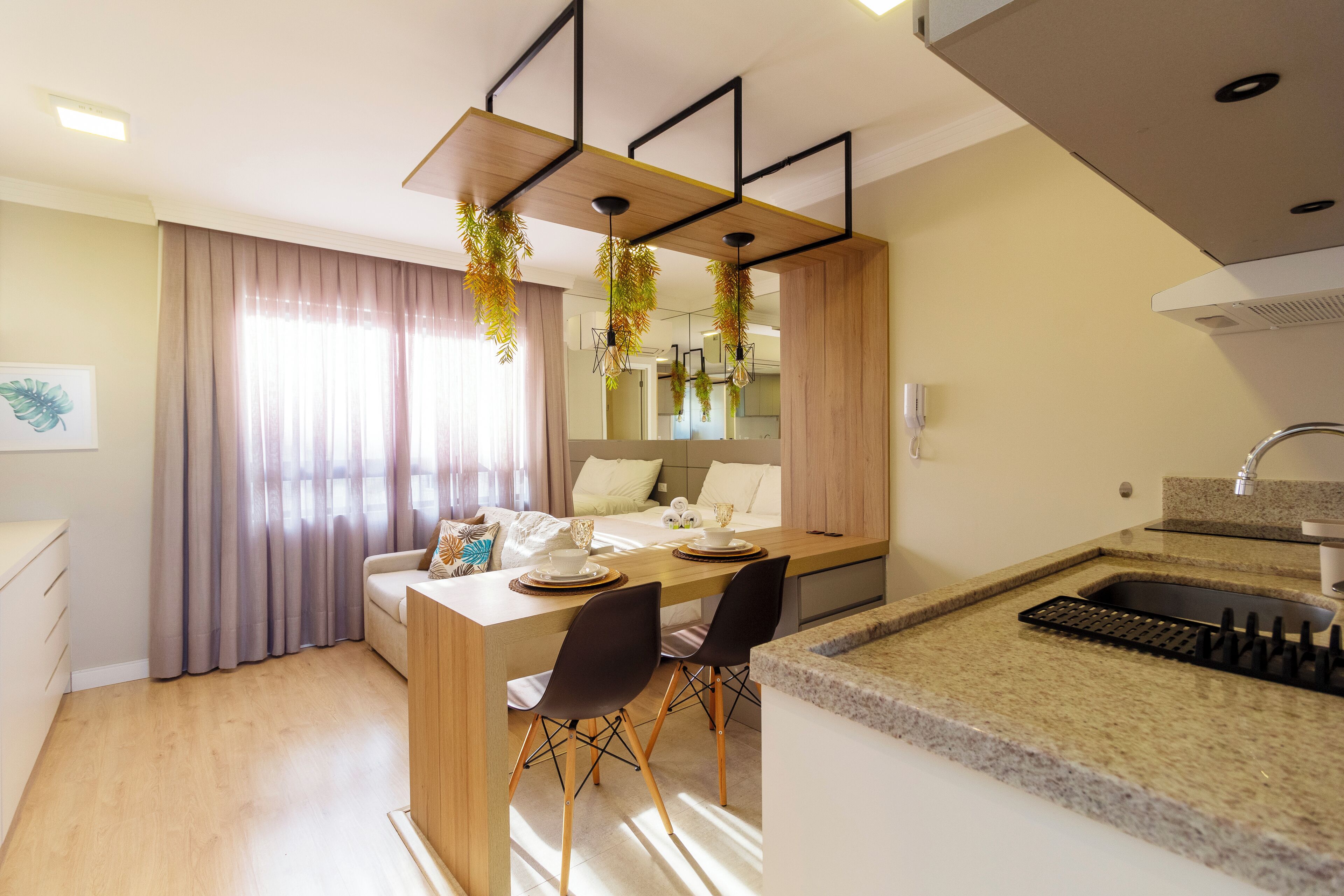 A modern kitchen with a granite countertop, a sink, and a dining area with a wooden table and chairs.