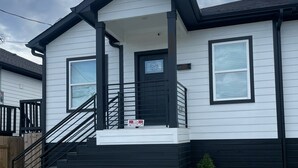 Et toetagers hus med en sort veranda, en trappe og et skilt, der siger 'Ingen parkering'.