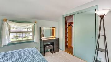A bedroom with a bed, a vanity with a mirror, a walk-in closet, and a floor lamp.