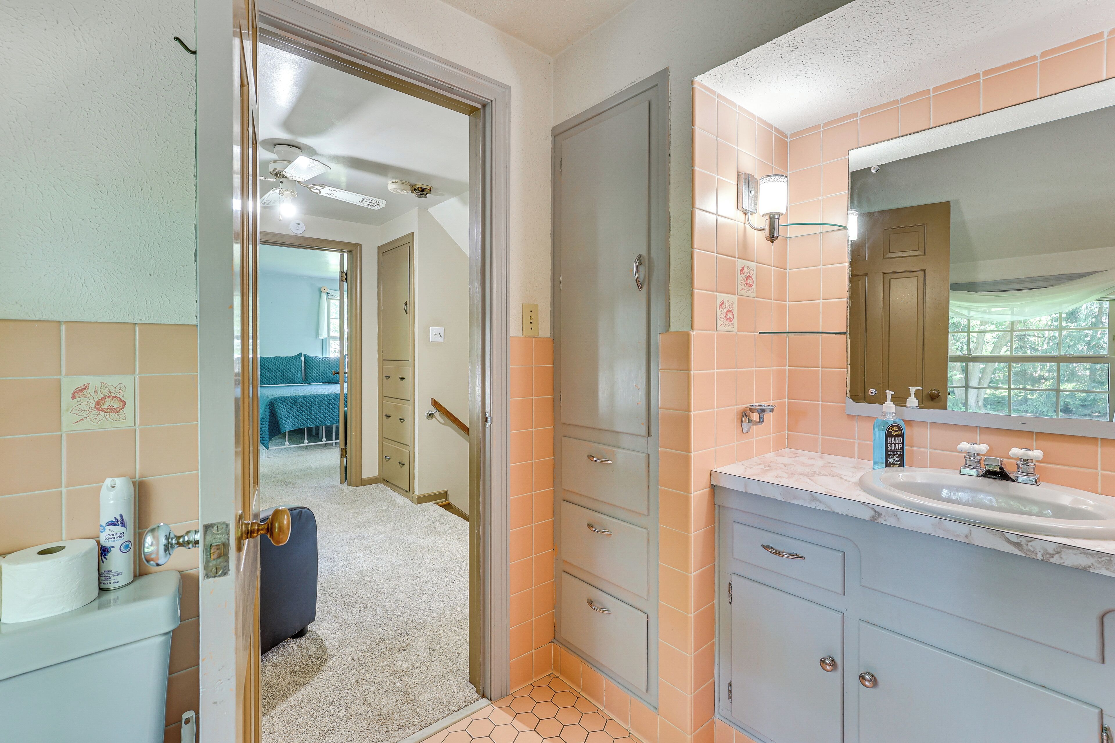 A bathroom with a sink, mirror, and toilet. There is a door leading to another room.