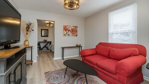 A living room with a red sofa, a TV, a small table, and a decorative rug. - Hallelujah Acres Side 2 (Georgetown)