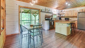 A spacious kitchen with wooden cabinets, a central island, and a dining area with chairs. - Pond & Fire Pit: Charming Log Cabin near Blue Rock (Philo)