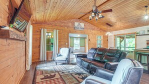 A cozy cabin interior with a wooden ceiling, leather sofa, and a dining area. - Pond & Fire Pit: Charming Log Cabin near Blue Rock (Philo)