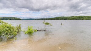 A calm lake with a sandy shore and some greenery in the foreground. - Walk to Norfork Lake: Guest House in Henderson (Henderson)