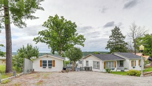 A row of single-story houses with a gravel driveway, surrounded by trees and a cloudy sky. - Walk to Norfork Lake: Guest House in Henderson (Henderson)