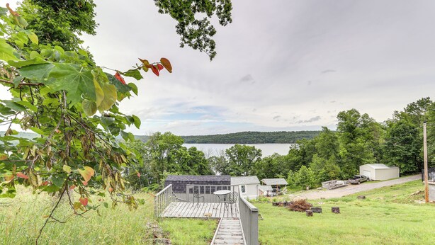 A wooden deck leading to a house with a view of a lake and hills in the background. - Walk to Norfork Lake: Guest House in Henderson (Henderson)