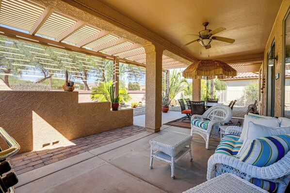A covered patio area with wicker furniture, a ceiling fan, and potted plants. - Step-Free, Sun City Grand Home w/ Resort Amenities (Surprise)