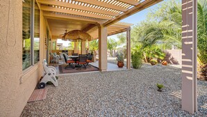 Une terrasse extérieure dotée d’une pergola, de sièges et d’une petite table.