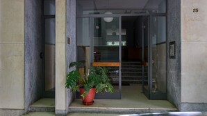 A building entrance with a glass door, a potted plant, and a staircase leading inside. - Prestige Lifestyle 3bd Apt in Kolonaki (Athina)