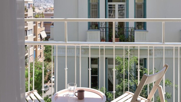 A balcony with a table, a chair, and a glass of water. - Prestige Lifestyle 3bd Apt in Kolonaki (Athina)
