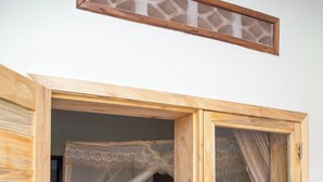A wooden four-poster bed with a canopy, a small wooden nightstand, and a tiled floor. - Eagle View Golf (Kigali)