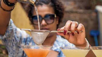 A person pouring a drink from a shaker into a martini glass.