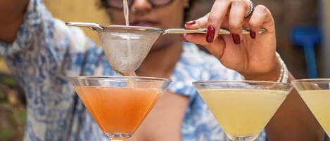 A person pouring a drink from a shaker into a martini glass.