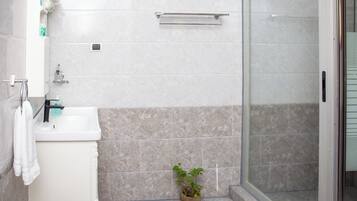 Une salle de bain avec un lavabo, un porte-serviettes et une plante en pot.