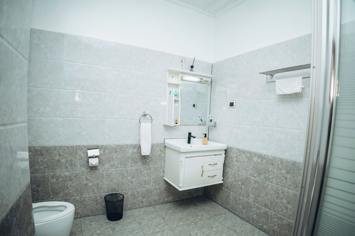 Et badeværelse med toilet, vask, spejl og håndklædestang.