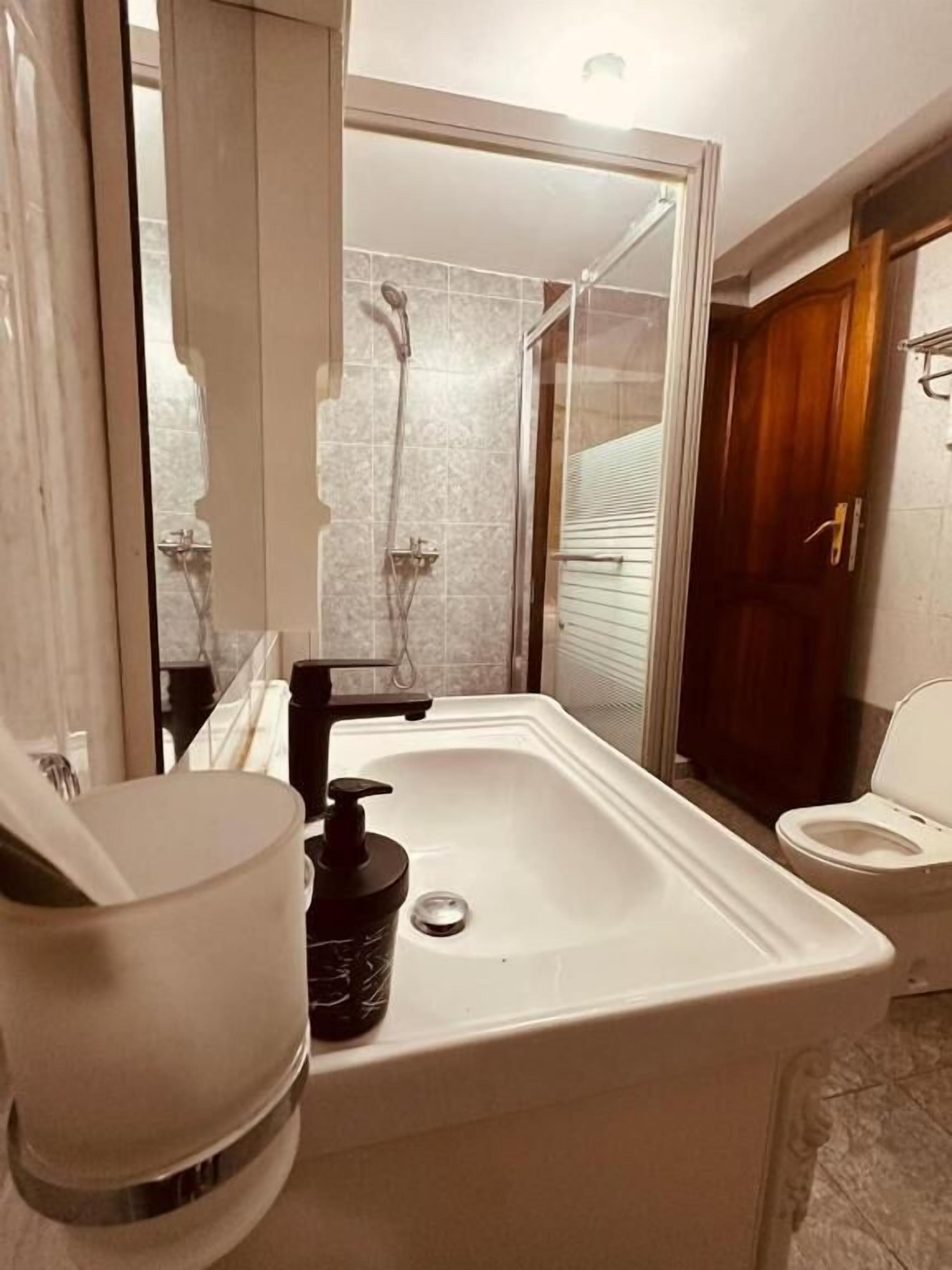 A bathroom with a sink, toilet, and shower area.