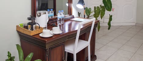 Un coin repas avec une table en bois, des chaises blanches, un grand miroir et une plante en pot.