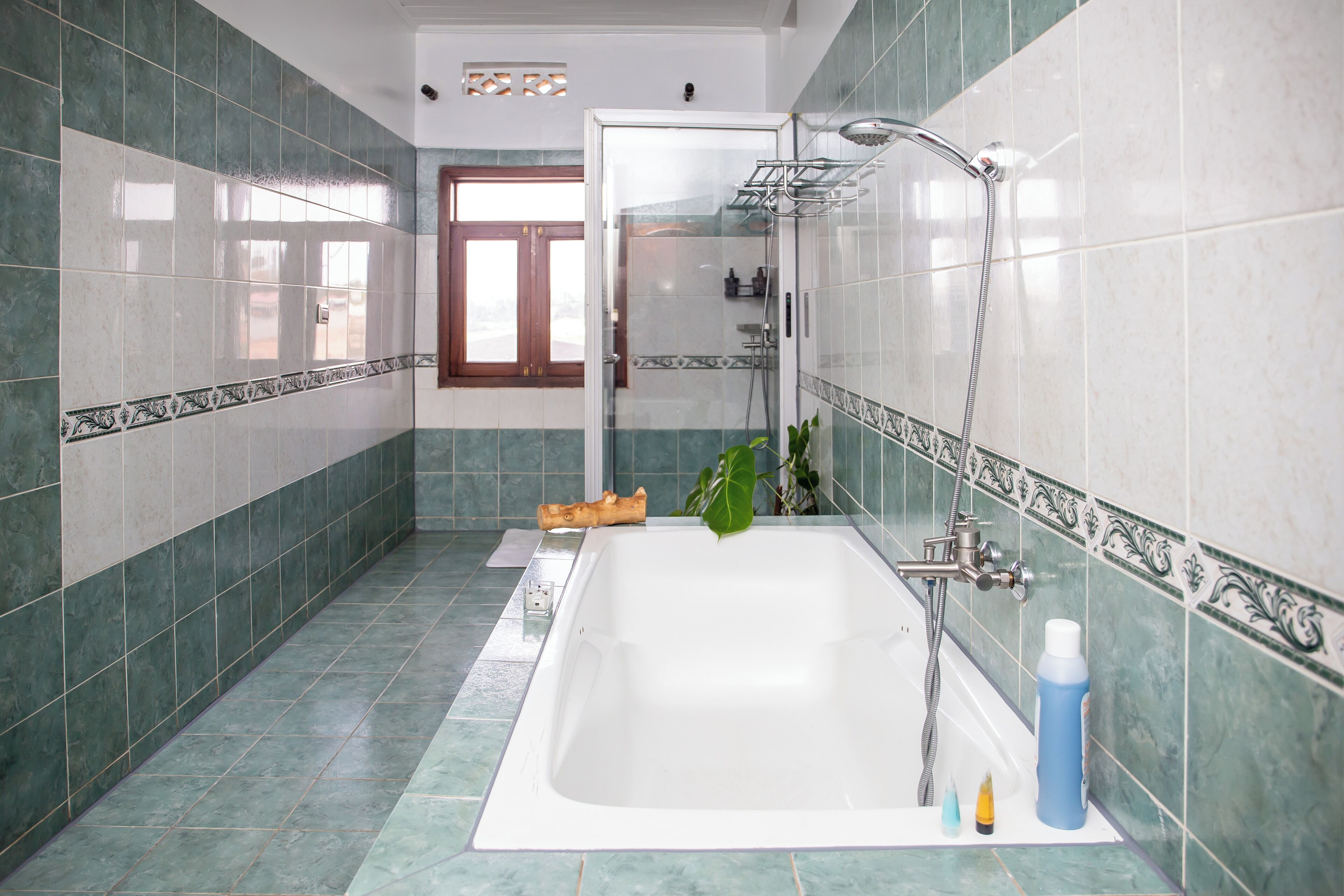 A bathroom with a bathtub, shower, and a window.