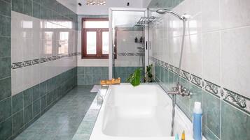 A bathroom with a bathtub, shower, and a window.