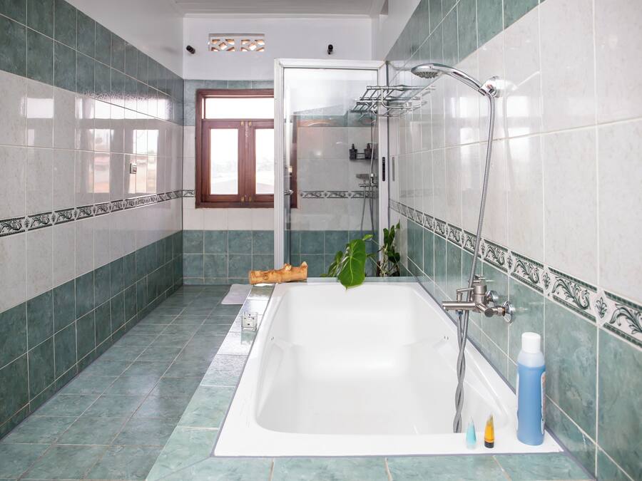 A bathroom with a bathtub, shower, and a window.