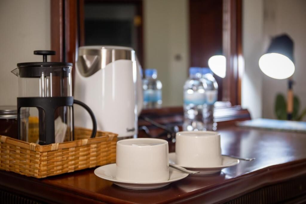 A coffee maker, a water dispenser, and two cups on a wooden table.