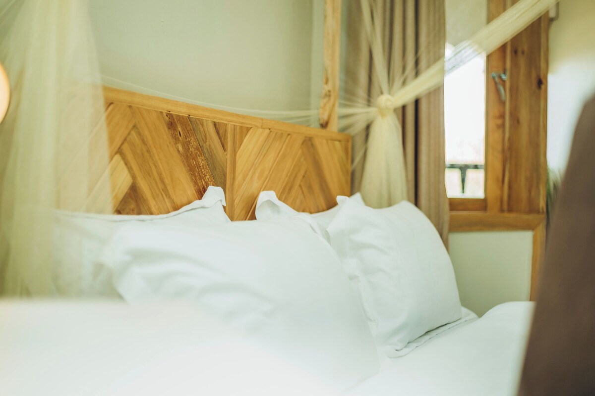 Un lit avec du linge de lit blanc et une tête de lit en bois.