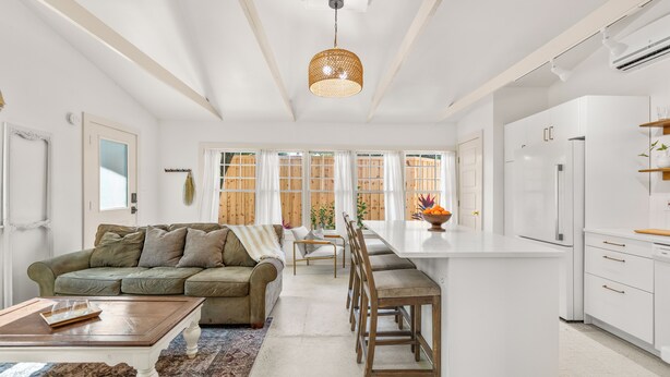A spacious kitchen with white cabinetry, a central island, and a dining area with a sofa and chairs. - Walk to Downtown - Luxe Backyard - Private + Peaceful Stay (St. Augustine)