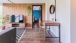 En moderne stue med trævæg, et fladskærms-tv, et spisebord og en hængende plante.