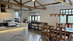 Una cocina con vigas de madera, una isla central y un comedor con sillas y una mesa de madera.