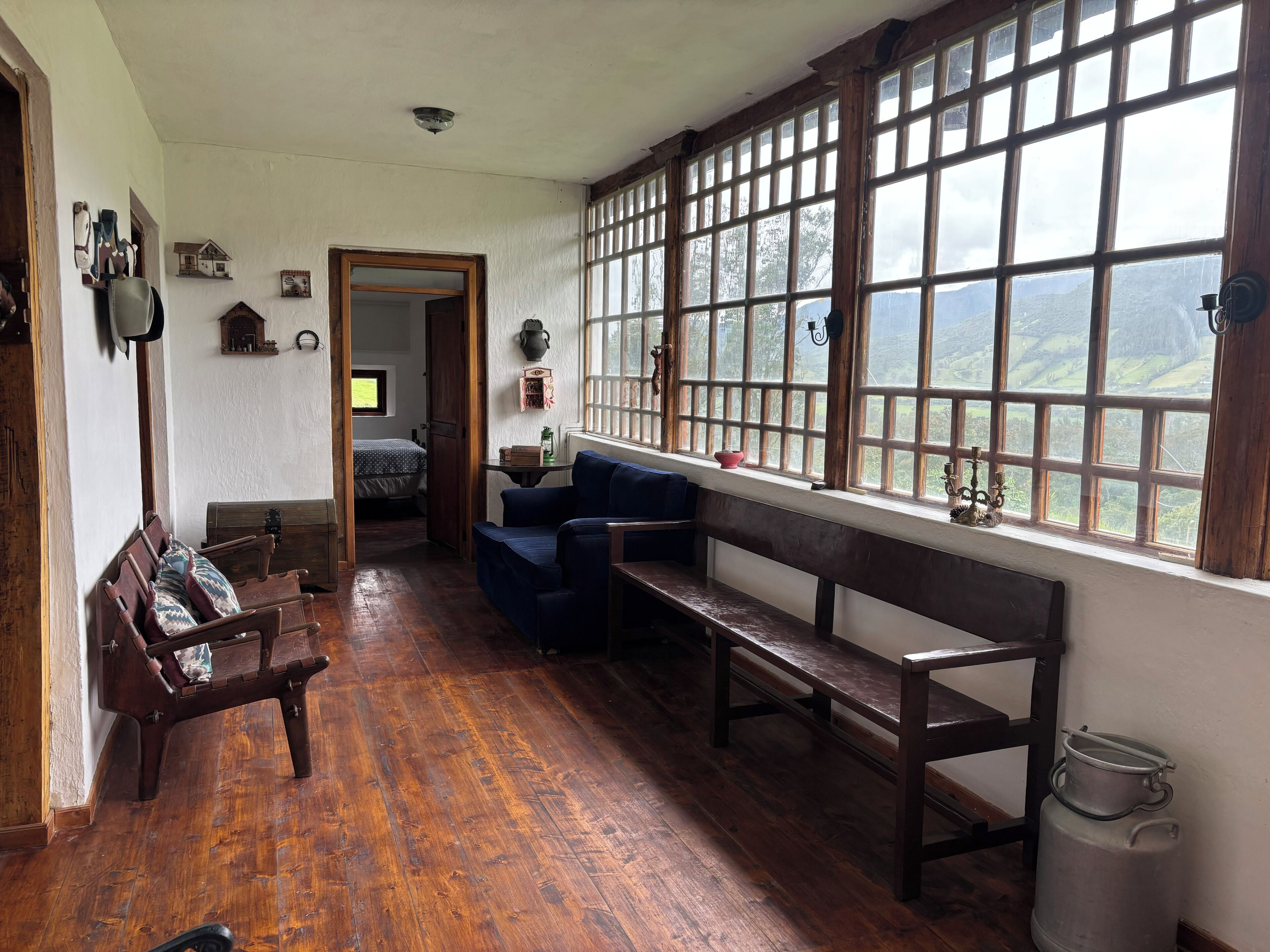 A cozy room with wooden benches, a sofa, and a large window offering a view of the outdoors.