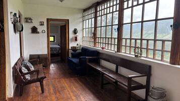 A cozy room with wooden benches, a sofa, and a large window offering a view of the outdoors.