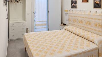 A bedroom with a bed, a wardrobe, a television, and a door leading to an outdoor area.