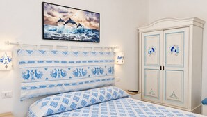 A bedroom with a bed, a nightstand, a wardrobe, and a wall-mounted picture. - Room-private Blue Apartment at Palma de (Sant'Antioco)