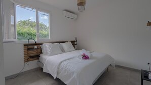 Une chambre à coucher comprenant un lit, une fenêtre, un appareil de climatisation et un luminaire suspendu.