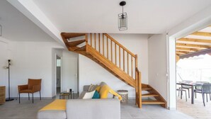 Un salon moderne avec un escalier en bois, un canapé et un coin repas.