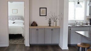 Een moderne keuken met grijze kastjes, een houten aanrechtblad en een raam met zonwering.