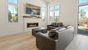Un salon moderne doté d’une cheminée, de grandes fenêtres et offrant une vue sur l’extérieur.