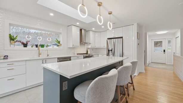 Una cucina moderna con isola centrale, sgabelli da bar e illuminazione a sospensione.