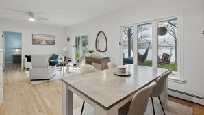 Un soggiorno moderno con angolo pranzo, un'ampia finestra vista all'esterno e una ventola a soffitto.